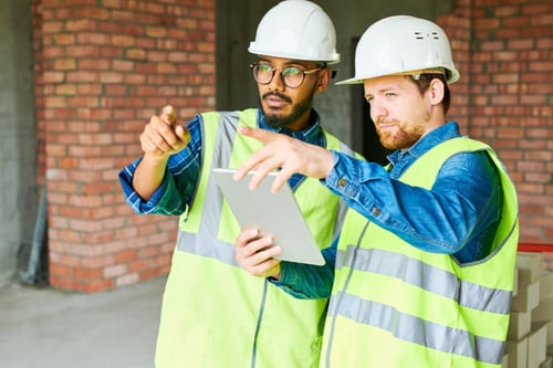 two construction workers pointing